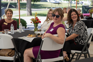 Women seated outside smiling under tent