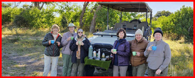 Six women in front of a utility vehicle, bundled up holding mugs of hot beverages.