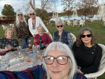 Women sitting outside on a sunny day drinking wine.